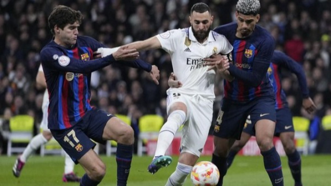 Pemain Real Madrid dijegal oleh dua pemain Barcelona.
